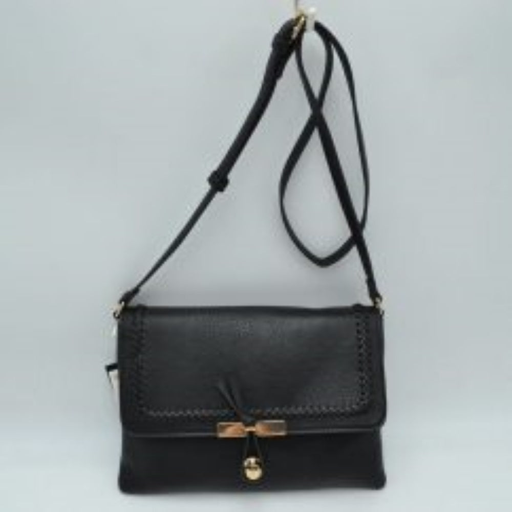 Black This stylish handbag features a textured pebbled finish with intricate whipstitch braided trim along the edges of the foldover flap, offering a classic aesthetic for everyday wear. The front closure is accented with a unique knotted strap detail paired with a polished metallic slider and charm. Designed with a slim, versatile profile, it includes a long, adjustable shoulder strap for comfortable hands-free cross-body carrying.