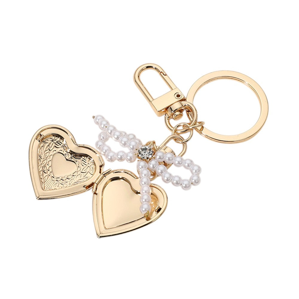 Cream Gold Pearl Beaded Bow Pointe Metal Heart Locket Bag Charm adds a touch of elegance to any bag. The pearl beads and metal heart locket create a stunning, timeless look. Perfect for adding a subtle pop of glamour to your everyday bag.