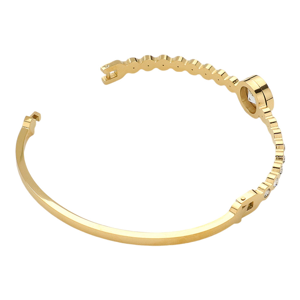 Gold Stainless Steel Round CZ Stone Bezel Hinged Bangle Bracelet. Made with high-quality stainless steel and featuring beautifully cut CZ stones in a bezel setting, this bangle adds a touch of elegance to any outfit. With a hinged design, it is easy to put on and take off for a comfortable fit. Elevate your style with this sophisticated accessory.