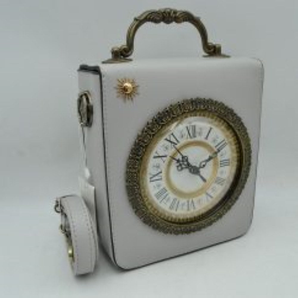 Grey This unique novelty handbag features a structured boxy silhouette in a light grey tone, centered around a prominent vintage clock design on the front panel that makes it a striking statement piece. The detailed clock face is styled with classic Roman numerals and elegant hands, beautifully enclosed within an intricate, antique bronze-tone textured circular frame and accented by a small gold sunburst stud in the upper corner.