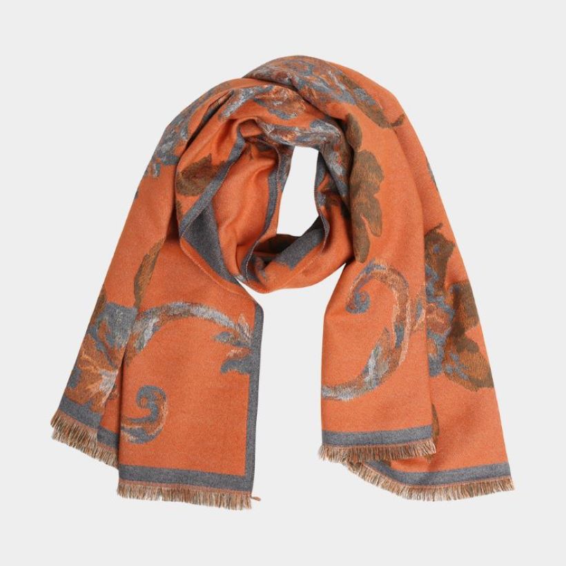 A soft scarf featuring an elegant floral print with a bordered edge and fringe finish. Lightweight yet cozy, this versatile accessory brings warmth and a touch of sophistication to casual and dressy outfits.