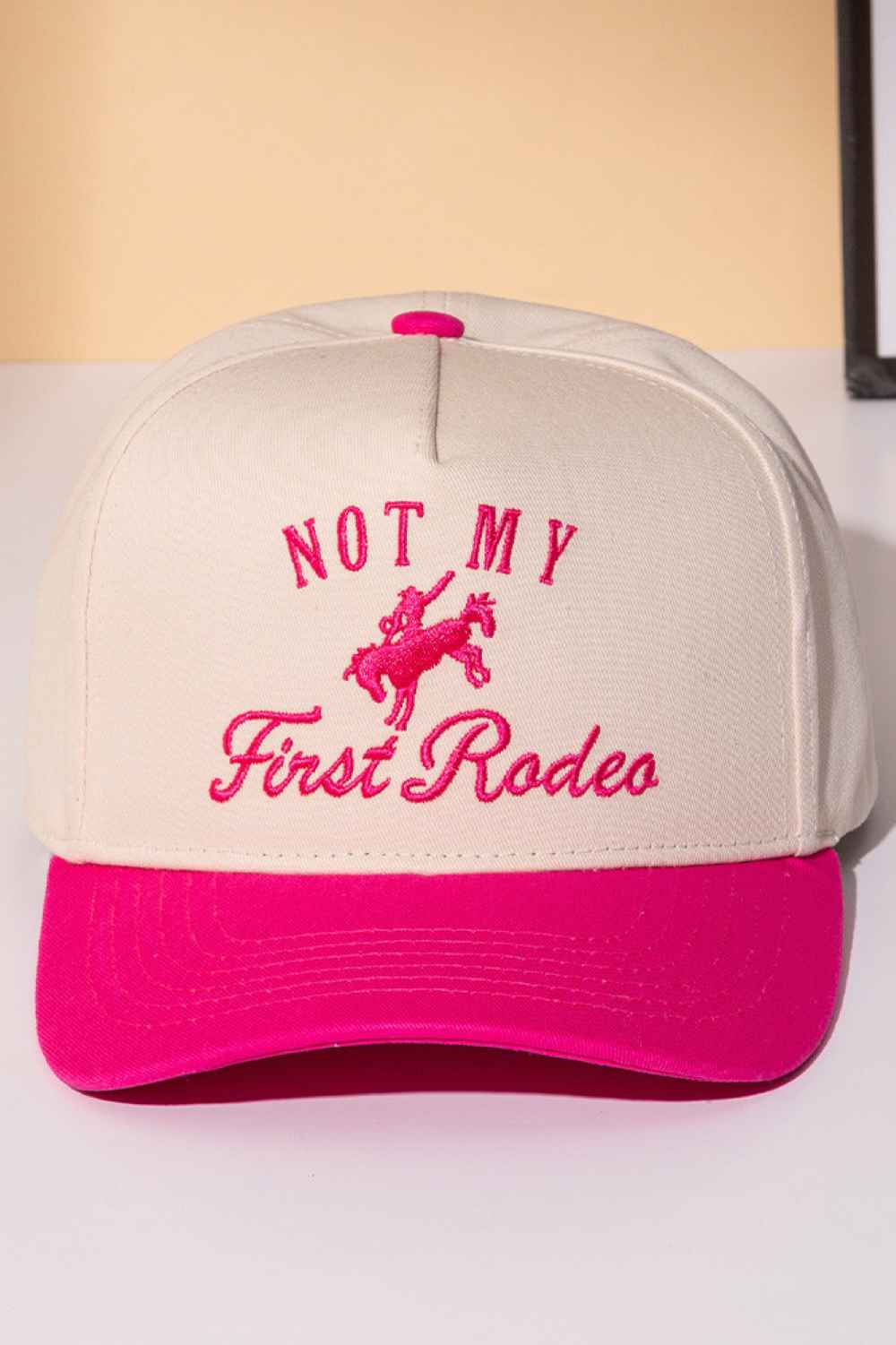 Pink Classic trucker cap with bold "NOT MY FIRST RODEO" embroidery across the front. Features a two-tone design that blends style with attitude. Crafted from 100% cotton for breathability and comfort. Snapback closure adjusts to fit most head sizes. Perfect for casual wear, outdoor adventures, or making a statement wherever you go.