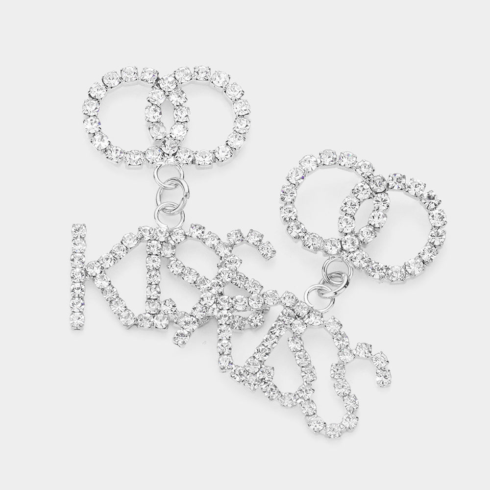 Rhodium KISS Rhinestone Embellished Message Dangle Earrings are the perfect accessory to add a touch of glamour to any outfit. The delicate dangle design adds movement and sparkle to your look, making you stand out from the crowd. Own these stunning earrings and shine like a star.