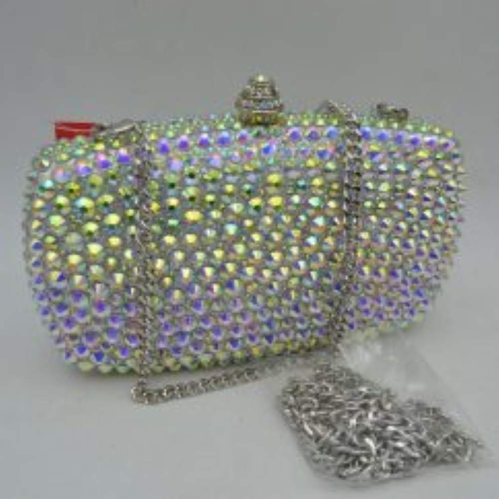 Silver This structured clutch bag features a heavily embellished exterior covered in rows of faceted, multi-dimensional studs that create a textured look suitable for elevated everyday styling or evening events. The compact design opens to a main storage compartment via a secure rigid frame and an ornamental, cylindrical top clasp set with matching small accents. For versatile carrying options, the piece is equipped with a metallic curb chain handle attached to top loop connectors
