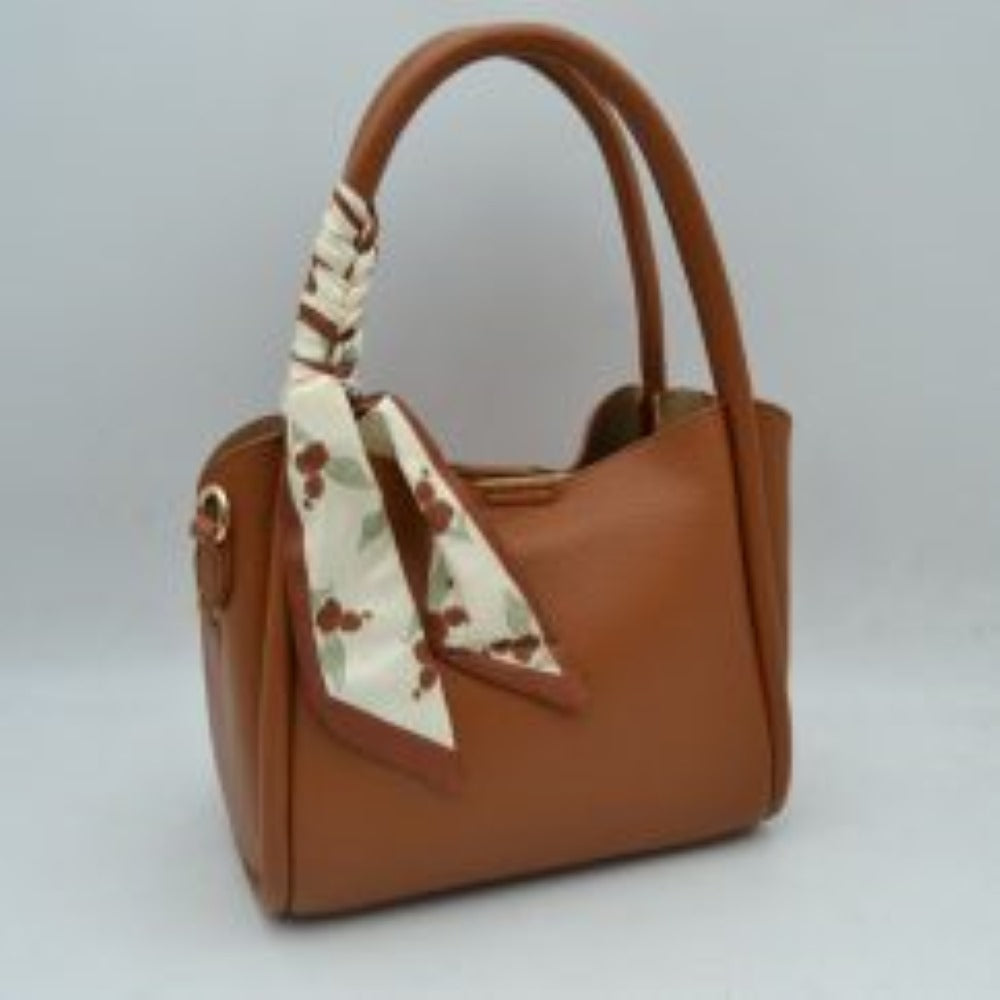 Tan Add a touch of retro sophistication to your everyday look with this beautifully contoured satchel handbag. Designed with a structured yet softly curved silhouette, this bag features a premium pebble-textured finish that resists daily wear while maintaining a polished aesthetic. The side handle is playfully wrapped with a removable black-and-white polka dot scarf, lending a timeless, feminine charm to the overall piece.