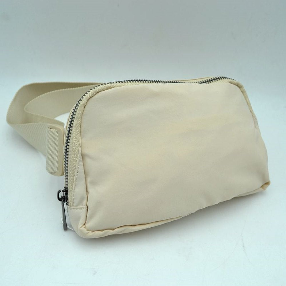 Beige This minimalist bag features a smooth, clean design ideal for versatile everyday use. The main storage compartment is secured by a curved top zipper with dual pulls for easy access to essentials. A wide, adjustable strap extends from the sides, complete with a matching slider to easily customize the fit for comfortable carrying.