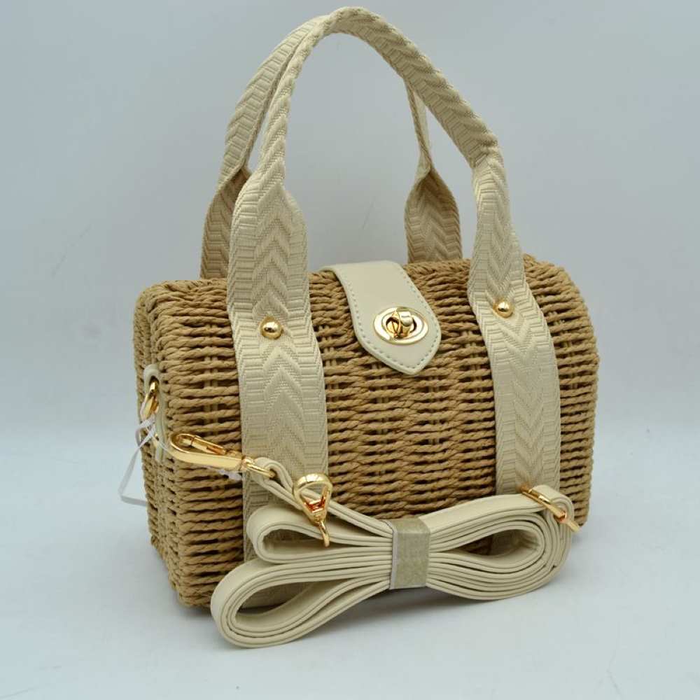 Beige This structured barrel-shaped handbag features a textured, tightly woven body designed for unique everyday style. It is equipped with dual top handles featuring a distinctive chevron pattern, which are secured to the front and back panels with polished metallic studs. A central tab with a smooth texture extends over the top opening, fastening securely with a metallic turn-lock closure on the front.