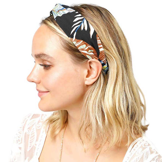 Black Tropical Leaf Patterned Twisted Headband, perfect for adding a touch of summer to any outfit. Crafted with a unique twisted design and featuring a vibrant tropical leaf pattern, this headband is both stylish and functional. Stay on-trend and keep your hair in place with this fashionable accessory.