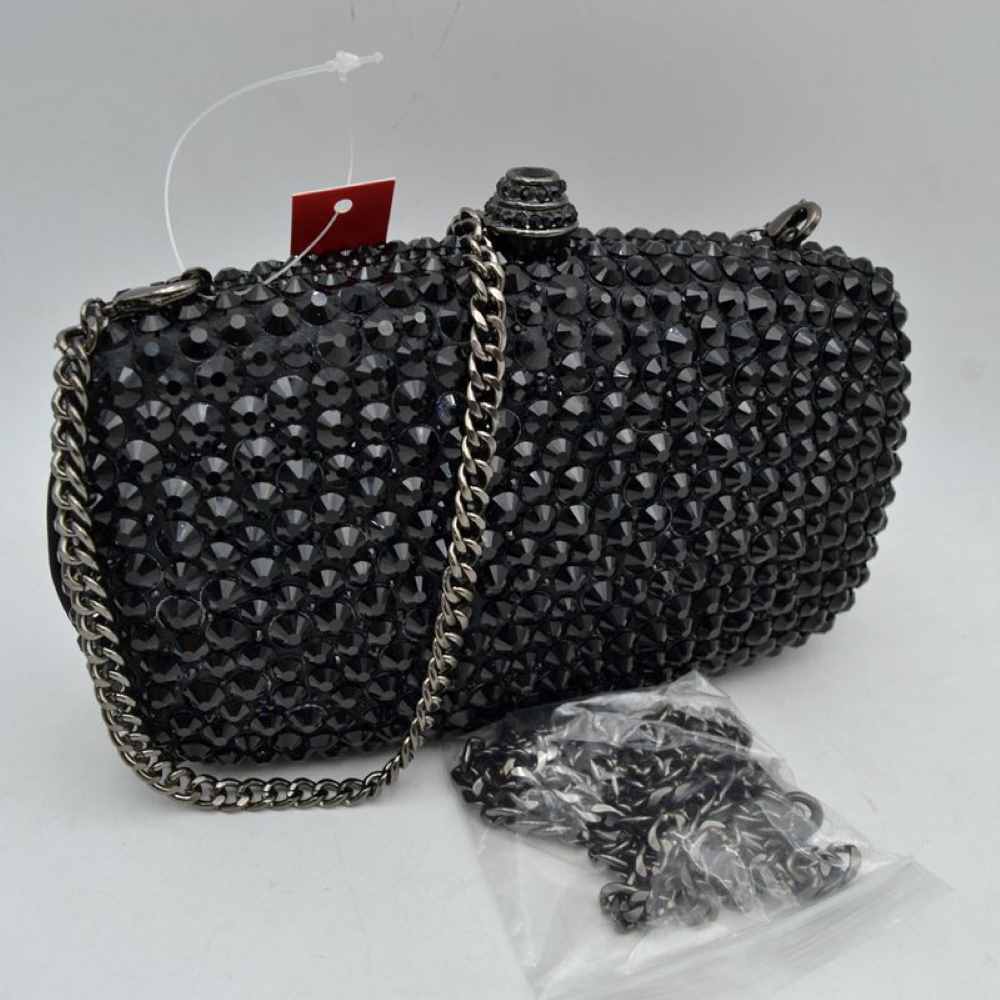 Black This structured clutch bag features a heavily embellished exterior covered in rows of faceted, multi-dimensional studs that create a textured look suitable for elevated everyday styling or evening events. The compact design opens to a main storage compartment via a secure rigid frame and an ornamental, cylindrical top clasp set with matching small accents. For versatile carrying options, the piece is equipped with a metallic curb chain handle attached to top loop connectors