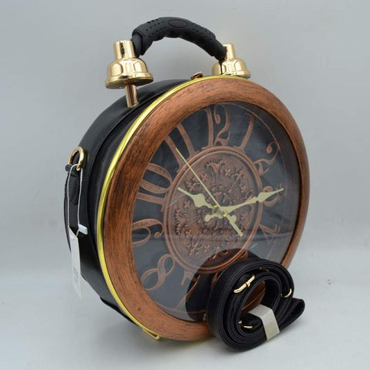 Black This unique novelty handbag features a structured round silhouette designed to look like a vintage twin-bell alarm clock, making it an exceptional statement piece. The prominent front panel showcases a large clock face detailed with oversized numbers and ornate gold-tone hands, beautifully enclosed within a wood-grain textured circular frame and a clear protective cover. Mimicking a classic alarm clock