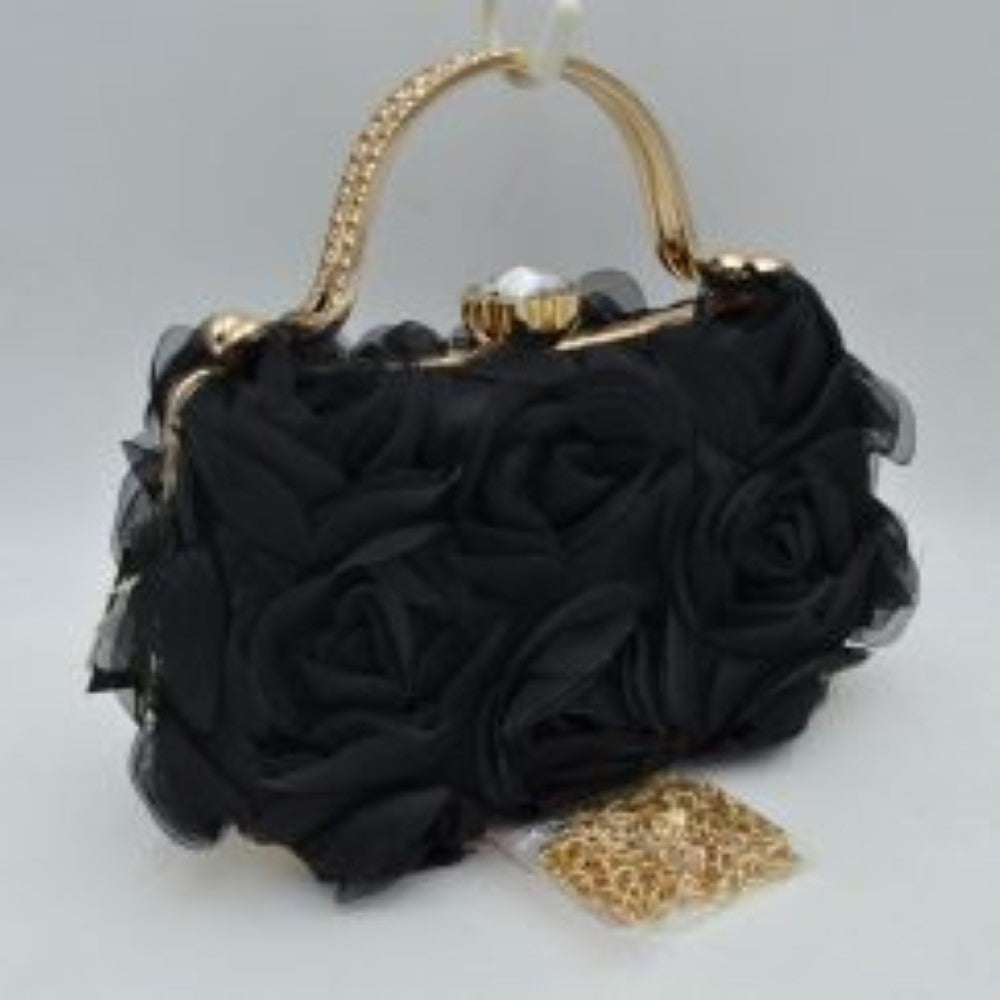 Black Make an elegant impression at your next formal event with this stunning evening clutch bag. The exterior features a beautiful arrangement of multi-dimensional, textured rosettes that create a soft floral pattern over a smooth base fabric. A polished, metallic top handle arches elegantly over the structured frame, while a prominent rhinestone-encrusted clasp closure sits at the top to secure your essentials with a touch of brilliant sparkle. Perfect for weddings, galas