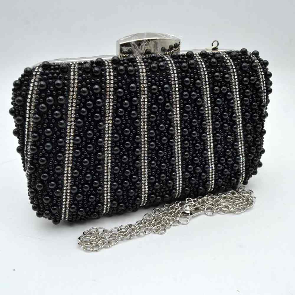 Black This sophisticated evening clutch bag features a hard-shell structured body covered entirely in glossy black beads, creating a rich textured finish. The design is elevated by vertical stripes of shimmering rhinestones running across the front panel for a touch of glamour. Ideal for formal events or special occasions, the main storage compartment is secured by a metallic top frame with a polished geometric clasp closure.