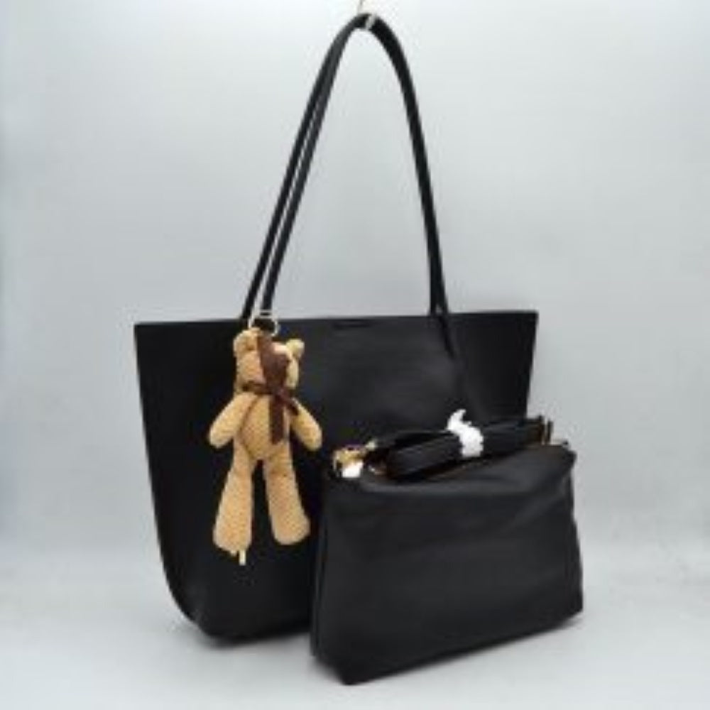 Black his classic tote bag features a subtly pebbled exterior texture with a relaxed yet structured silhouette that is ideal for everyday use. Designed with a clean, open top for convenient access to the spacious main storage compartment, the bag is equipped with dual long, slim shoulder handles securely anchored to the interior panels. A decorative plush bear charm with a tiny bow sits on the front