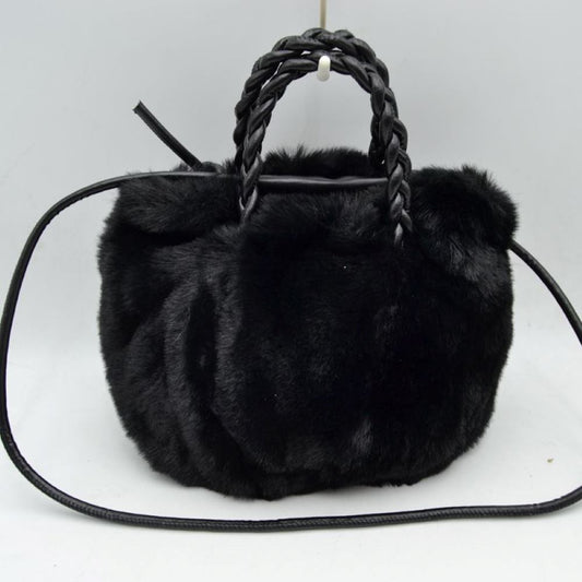 Black This soft everyday bucket-style handbag features a densely textured, plush exterior that offers a cozy aesthetic for daily use. Designed with a structured yet flexible silhouette, it features dual braided top handles for comfortable hand carrying alongside a slender, long shoulder strap that provides hands-free convenience. The top opening reveals a spacious central storage compartment ideal for organizing essential items