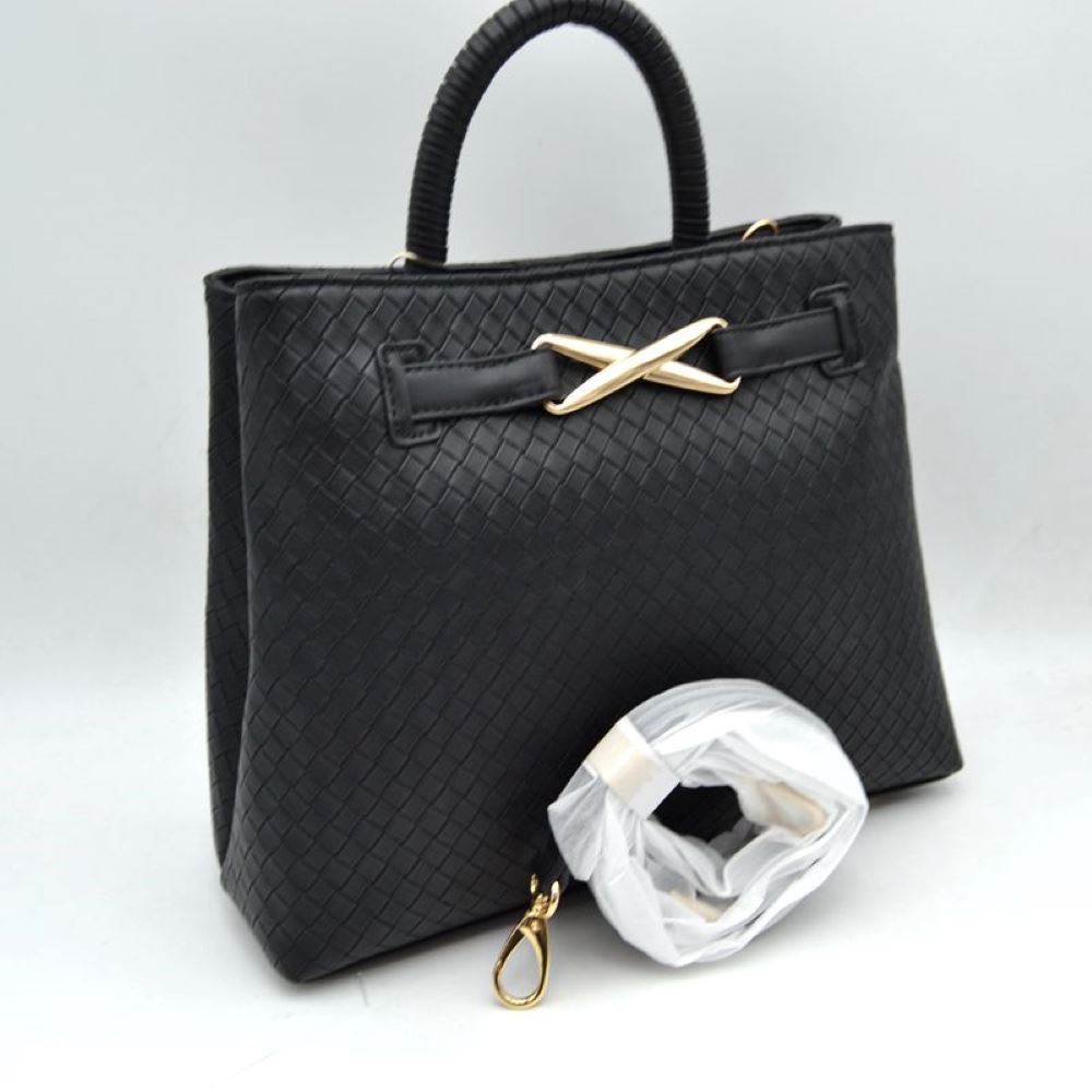 Blak This structured satchel features an intricately textured, woven pattern across the exterior, making it a sophisticated choice for elevated everyday use. The front panel is accented by a decorative horizontal band joined together with a prominent, metallic X-shaped hardware detail. Built with a sturdy, rounded top handle for a classic handheld carry, the bag also includes a main storage compartment and a detachable long shoulder strap secured by metallic clasps