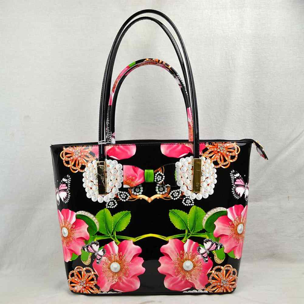 Black This eye-catching tote bag features a vibrant, high-gloss finish with a striking print of large pink blossoms, green leaves, butterflies, and rhinestone-style details set against a sleek black patent background. The front is charmingly accented with a printed bow and faux-pearl cluster motif, adding a playful touch of elegance. Designed with a structured, spacious silhouette, it features a secure top zipper closure to keep your essentials safe and is completed with slim