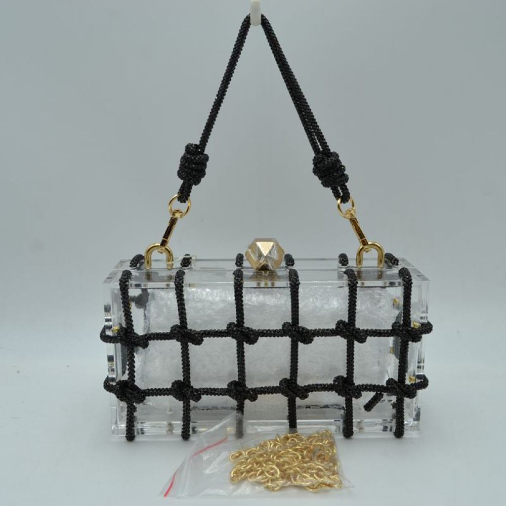 Black This unique everyday box clutch bag features a transparent structured body enclosed in a distinctive knotted cage overlay. Designed for specialized daily or evening use, the main storage compartment is secured by a top frame with a geometric metallic clasp closure. It offers versatile carrying options, equipped with a flexible cord top handle attached to the top panels via polished metal loops, alongside a separate metallic chain strap included at the base.