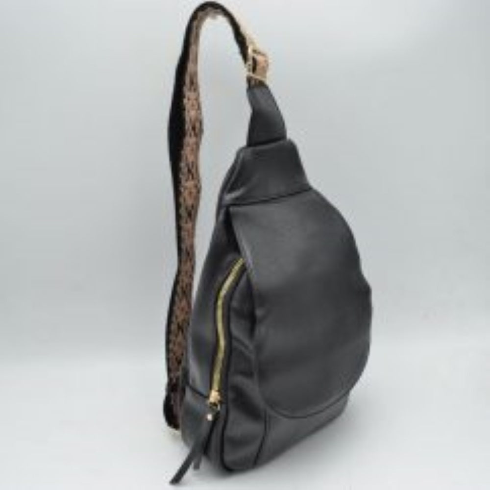 Black This functional sling bag features a teardrop silhouette designed for comfortable everyday use and hands-free convenience. It offers organized storage, including a main zippered compartment with metallic zipper hardware and pull tabs, complemented by a front flap closure section. The wide, adjustable shoulder strap showcases an intricate patterned weave and includes a metallic slide buckle for a customizable fit across the body.
