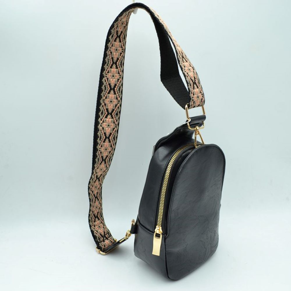 Black This compact sling backpack features a smooth textured finish and a contoured, teardrop-shaped silhouette designed for casual everyday use. It includes a primary storage compartment that secures with a prominent gold-tone zipper and a flat pull tab for easy access to essentials. A distinctive, wide shoulder strap decorated with an intricate geometric pattern connects via gold-tone metal clips to various anchor loops, allowing for adjustable and versatile cross-body or over-the-shoulder wear.