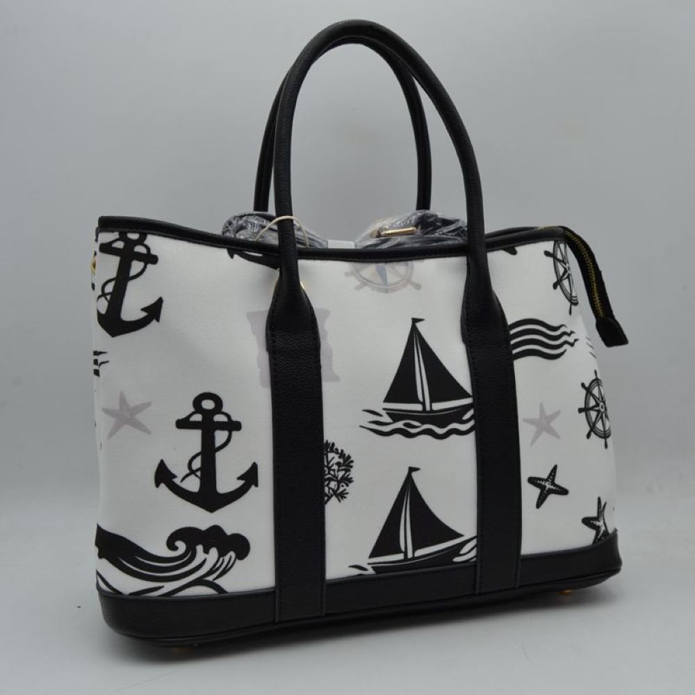 Black Set sail with this nautical-inspired canvas tote. Featuring a crisp backdrop decorated with a classic print of anchors, sailboats, ship wheels, and ocean waves, this bag is the perfect accessory for coastal getaways or adding maritime flair to your daily ensemble. Framed with structured textured trim, it balances casual resort style with sharp, everyday functionality. 
