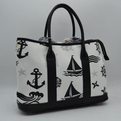Black Set sail with this nautical-inspired canvas tote. Featuring a crisp backdrop decorated with a classic print of anchors, sailboats, ship wheels, and ocean waves, this bag is the perfect accessory for coastal getaways or adding maritime flair to your daily ensemble. Framed with structured textured trim, it balances casual resort style with sharp, everyday functionality. 