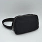 Black This minimalist bag features a smooth, clean design ideal for versatile everyday use. The main storage compartment is secured by a curved top zipper with dual pulls for easy access to essentials. A wide, adjustable strap extends from the sides, complete with a matching slider to easily customize the fit for comfortable carrying.