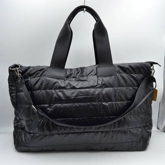 Black Upgrade your travel gear with this exceptionally spacious, lightweight weekender duffel bag, perfect for overnight trips, gym sessions, or casual weekend getaways. Featuring a stylish horizontally quilted puffer design, this bag combines a cozy, modern aesthetic with highly practical function. It is designed with wide, durable webbed top handles for a comfortable grip, alongside a matching adjustable and detachable shoulder strap secured by polished metallic clasps for easy hands-free carrying.