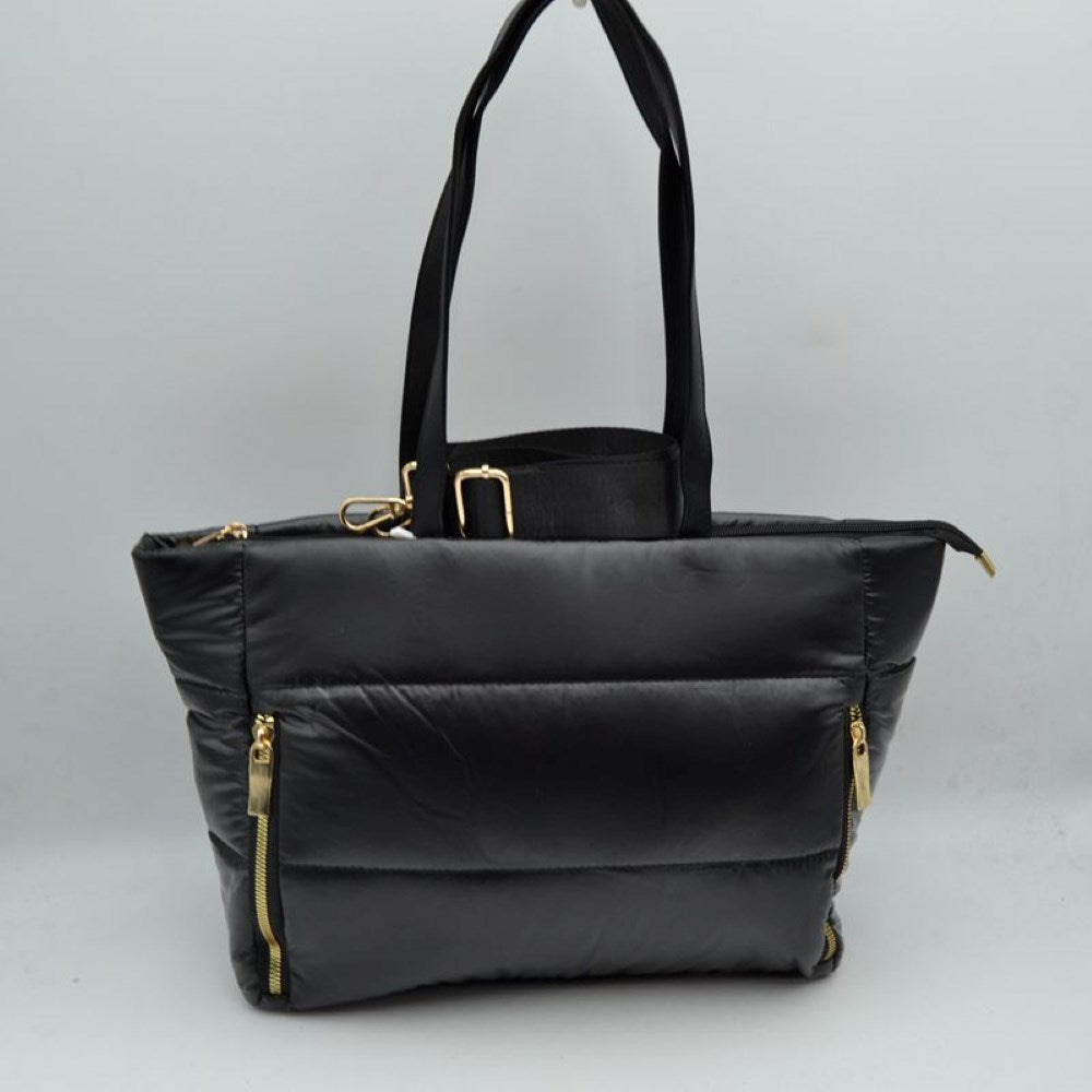 Black This versatile tote bag features a modern puffer design with horizontal quilted panels and a sleek satin-like finish, making it a stylish choice for everyday organization. It is equipped with dual flat shoulder handles for comfortable carrying, alongside a secondary adjustable fabric crossbody strap attached with metallic gold-tone hardware. The main storage compartment secures with a full top zipper closure