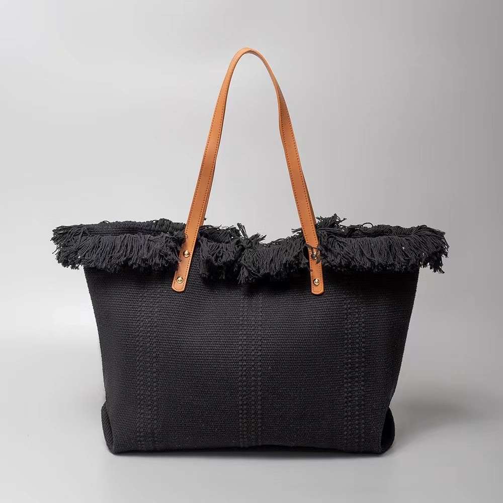 bLACK This spacious tote bag features a finely textured main body adorned with an eye-catching, voluminous fringe trim entirely wrapping around the upper opening. Designed for versatile everyday use, the bag is equipped with dual flat shoulder straps anchored securely to the front and back panels by metallic rivets.