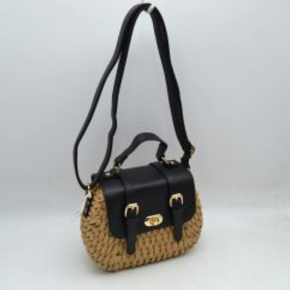 Black This charming satchel features a woven straw body paired with a smooth faux leather foldover flap, making it a stylish choice for warm-weather outings. It is detailed with dual decorative buckle straps on the front along with a secure gold-tone turn-lock closure. Designed for versatile wear, it includes a sturdy top handle for handheld carrying and a long, adjustable shoulder strap for comfortable hands-free crossbody or shoulder styling.