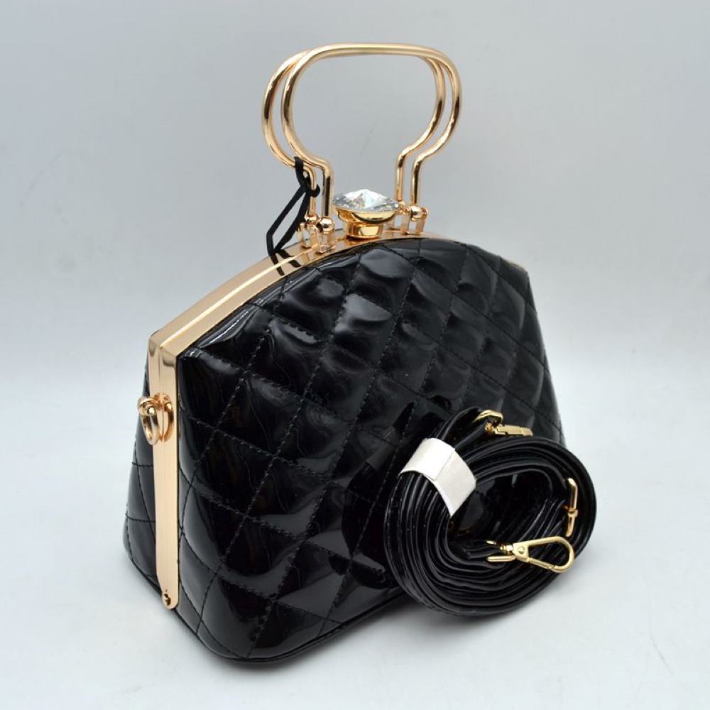 Black This structured handbag features a glossy, quilted exterior pattern that adds texturing to its rigid silhouette for everyday use. It is styled with distinctive metallic top handles and a secure upper storage compartment accessible through a solid frame opening. An ornamental crystal-like clasp sits prominently at the top closure, while side hardware rings accommodate the included matching detachable shoulder strap with metallic clips for multi-way wear.