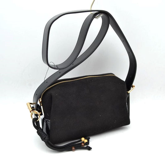 Black This sleek crossbody bag balances a structured design with a soft matte texture for an understated daily accessory. It features a compact, rectangular body secured by a top-zipper closure that keeps essential items neatly contained. A wide, smooth shoulder strap connects via metallic side loops, allowing for comfortable hands-free carrying. The minimalist look is accented by a decorative knotted cord element attached to the side hardware