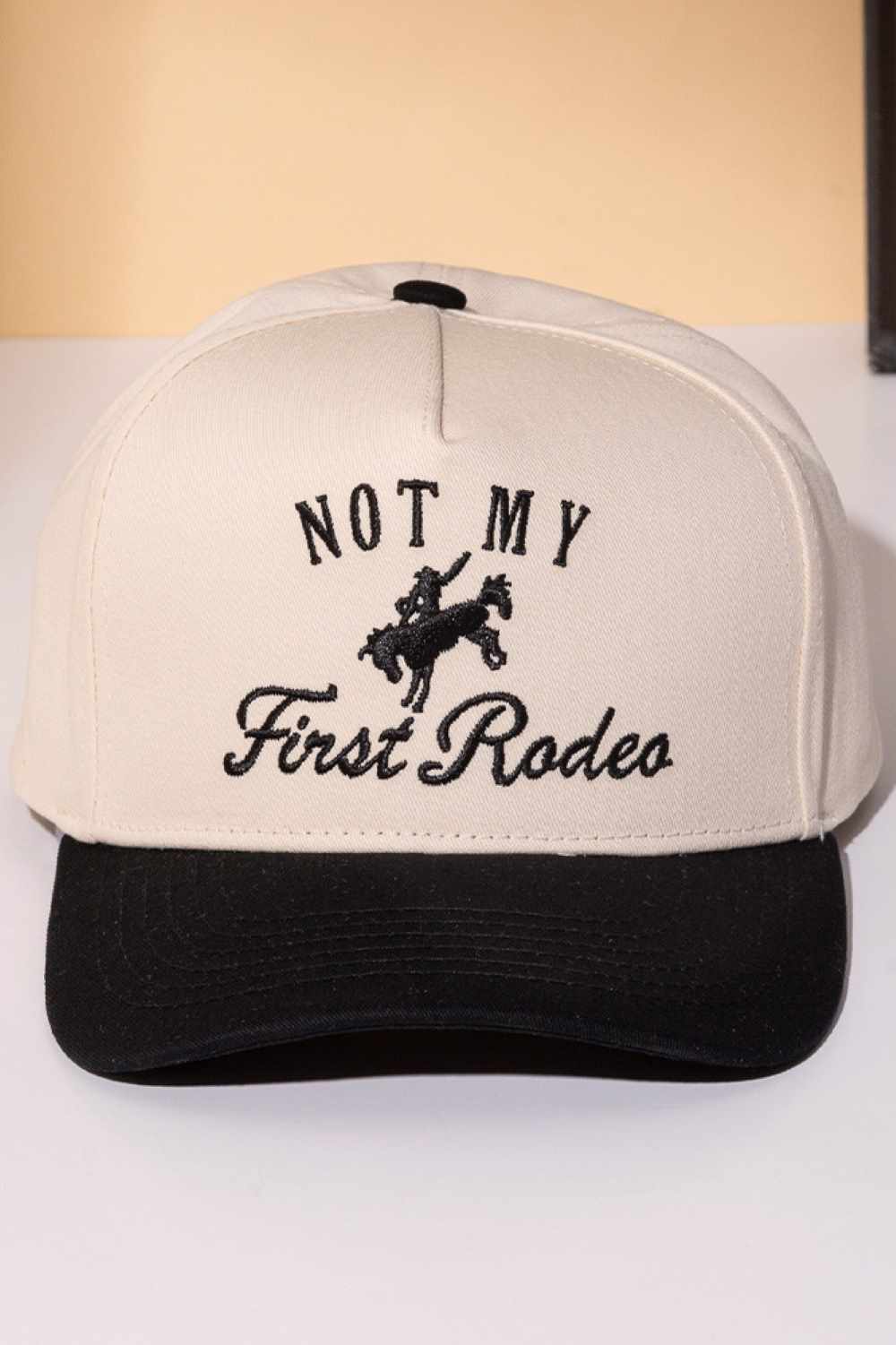 Black Classic trucker cap with bold "NOT MY FIRST RODEO" embroidery across the front. Features a two-tone design that blends style with attitude. Crafted from 100% cotton for breathability and comfort. Snapback closure adjusts to fit most head sizes. Perfect for casual wear, outdoor adventures, or making a statement wherever you go.