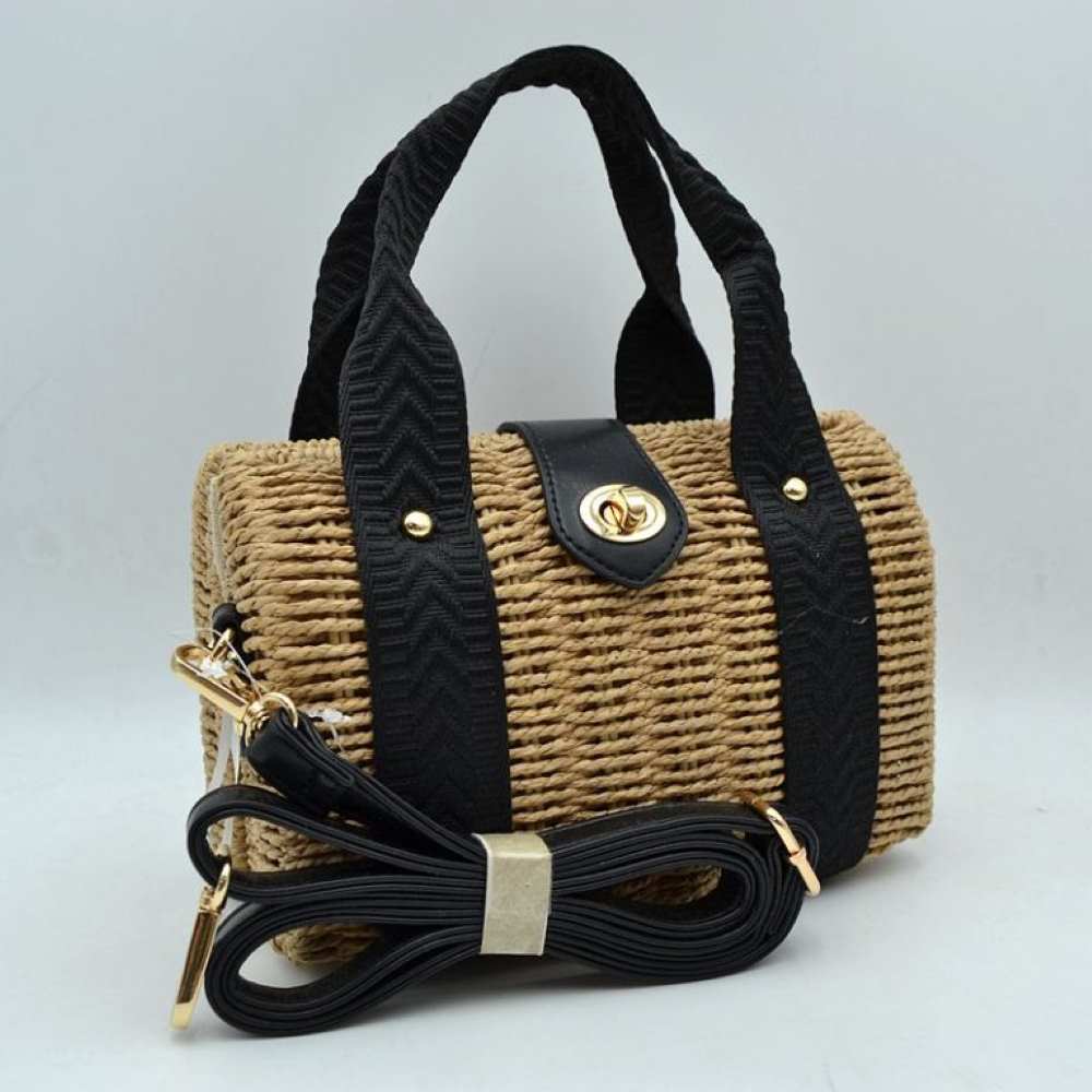 Black This structured barrel-shaped handbag features a textured, tightly woven body designed for unique everyday style. It is equipped with dual top handles featuring a distinctive chevron pattern, which are secured to the front and back panels with polished metallic studs. A central tab with a smooth texture extends over the top opening, fastening securely with a metallic turn-lock closure on the front.