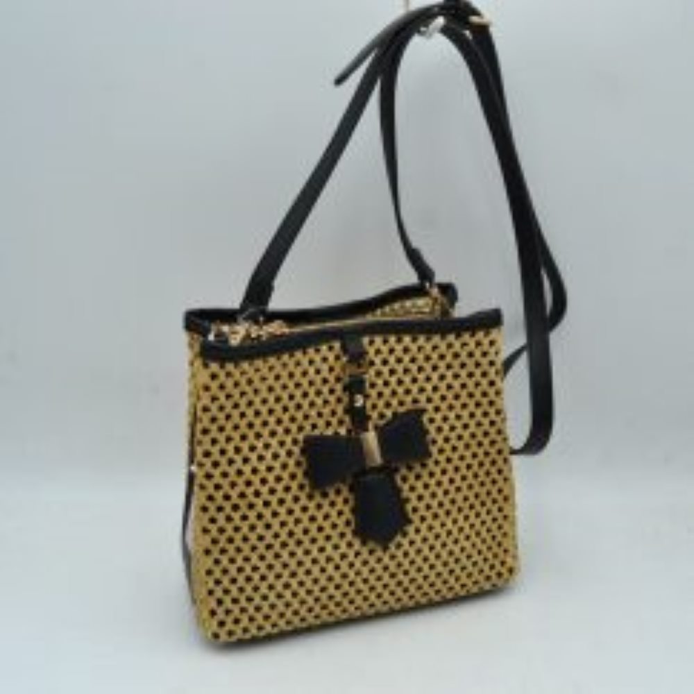 Black This structural crossbody bag features an intricate, open-weave mesh pattern across its body, offering an eye-catching and distinctive look for everyday use. A contrasting central vertical tab on the front panel is highlighted by a structured decorative bow accent anchored with metallic hardware. Built for easy organization, the bag contains multiple secure storage compartments including dual top zippers, while a long, adjustable slim shoulder strap loops smoothly over the top to provide comfortable