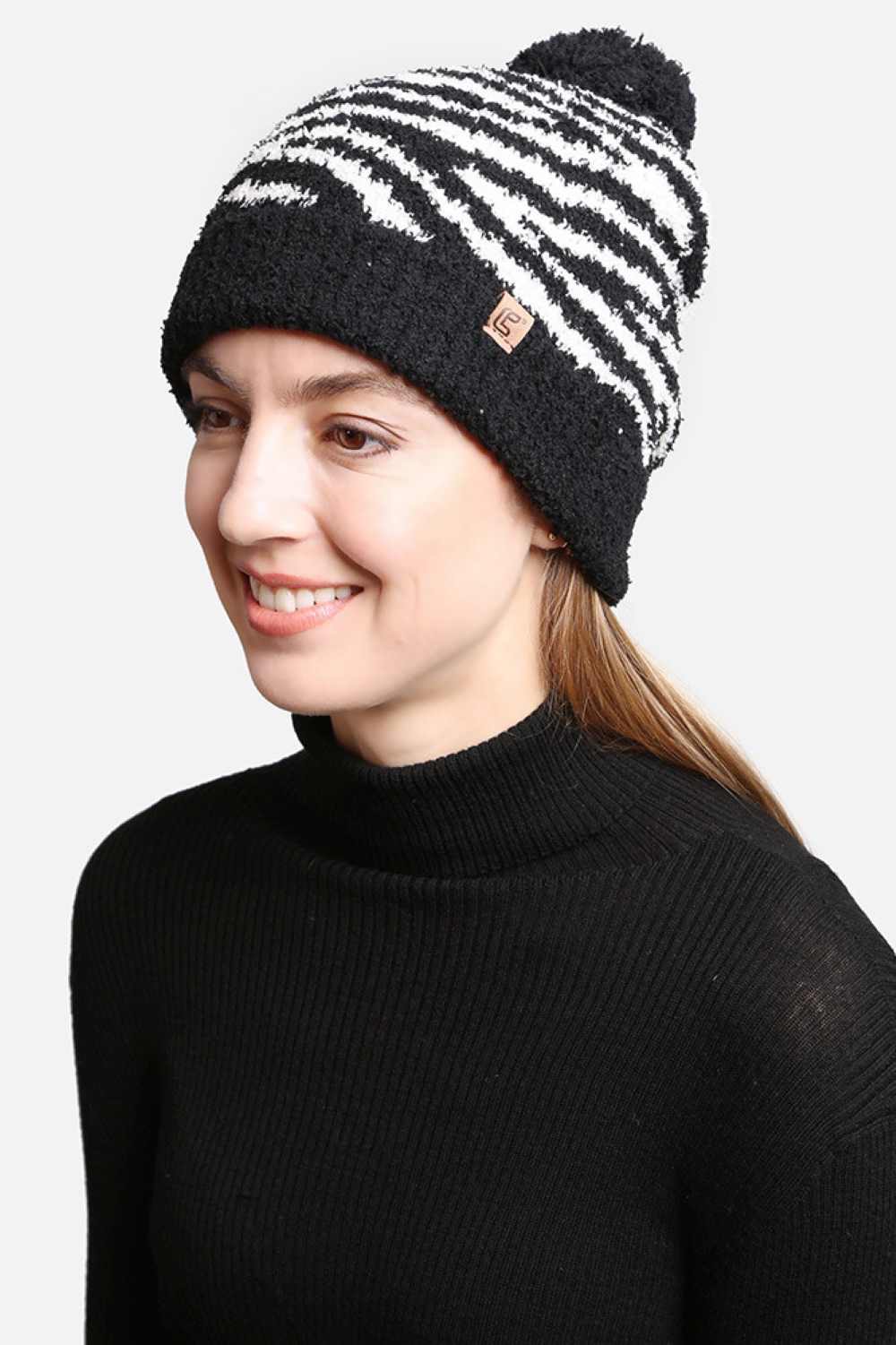 Black The Zebra Knit Pom Pom Lining Beanie features a bold zebra pattern that adds a fun, statement look to your winter outfit. Designed with a soft inner lining and a fluffy pom pom detail, it provides extra warmth, comfort, and a secure fit on cold days.