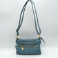 Blue This functional crossbody bag is designed for organized everyday use, featuring a textured exterior equipped with multiple secure storage compartments. The front panel includes a convenient horizontal zippered pocket accented with an oversized metallic zipper pull, situated beneath a decorative horizontal band detailed with metallic studs and loops.