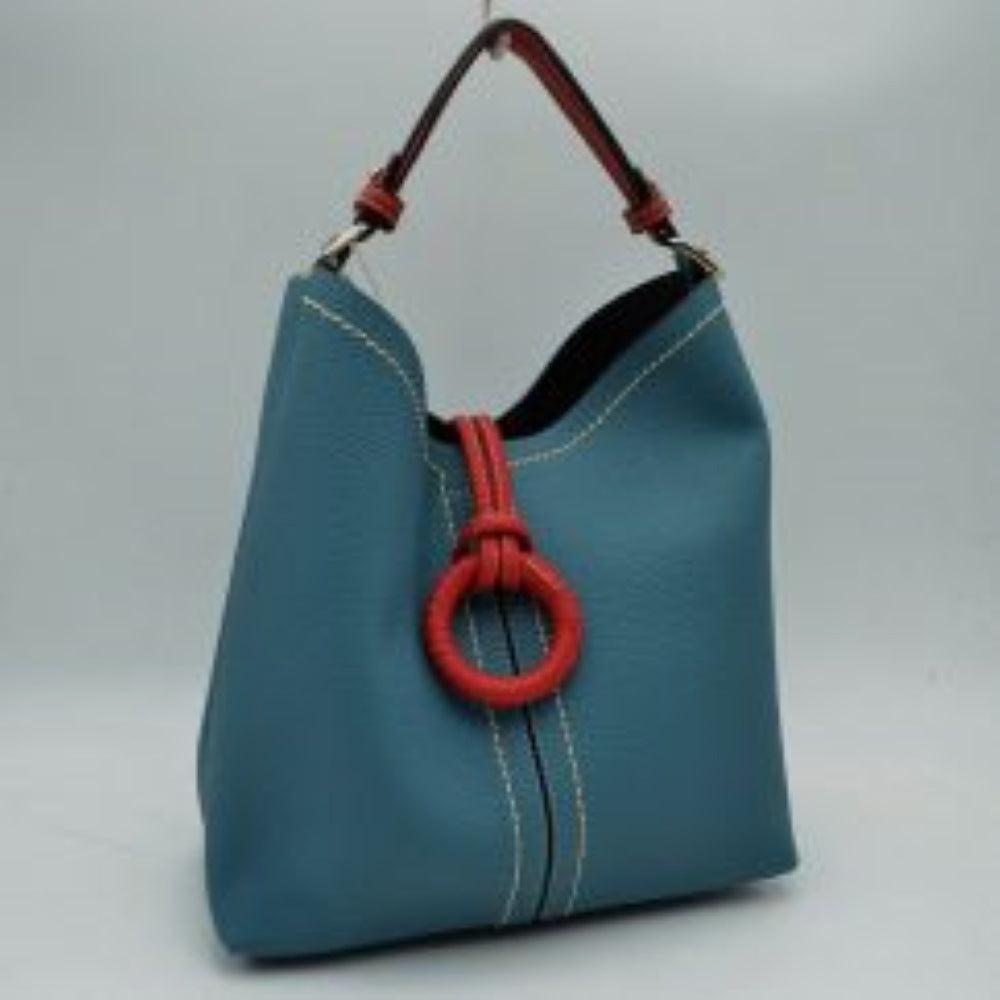 Blue This structured everyday bucket bag features a pebbled textured body with a distinctive curved, dip-top opening and prominent contrast stitching details along the front panel. It is designed with a singular flat top handle anchored to the sides by polished metal hardware loops for comfortable carrying. A central loop strap extends from the back to the front
