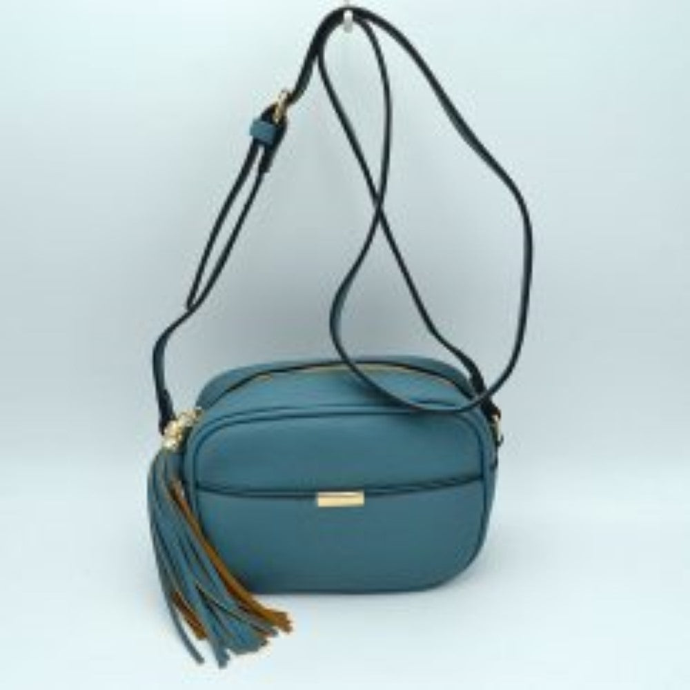 Blue This sophisticated crossbody bag features a structured camera-bag silhouette crafted from a textured pebbled faux leather in a neutral beige tone, making it a versatile addition to any wardrobe. The clean-lined front is detailed with a subtle open slip pocket highlighted by a polished, gold-tone metal hardware accent at the center. Secured by a smooth top-zipper closure, the bag is finished with an adjustable shoulder strap and a dramatic