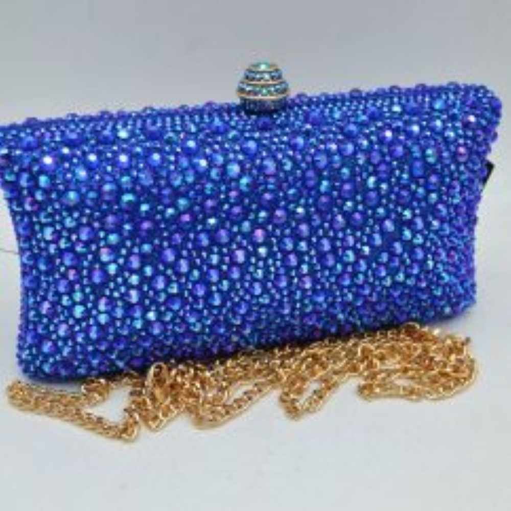 Blue This elegant box clutch bag features an all-over array of faceted, shimmering rhinestone embellishments that fully cover the exterior for a textured, light-catching look. Designed for evening or special occasion use, the structured frame includes a secure top clasp closure with a tiered, decorative knob that easily snaps open to access the main storage compartment. A matching, detachable metallic link chain strap with a secure lobster clasp is included