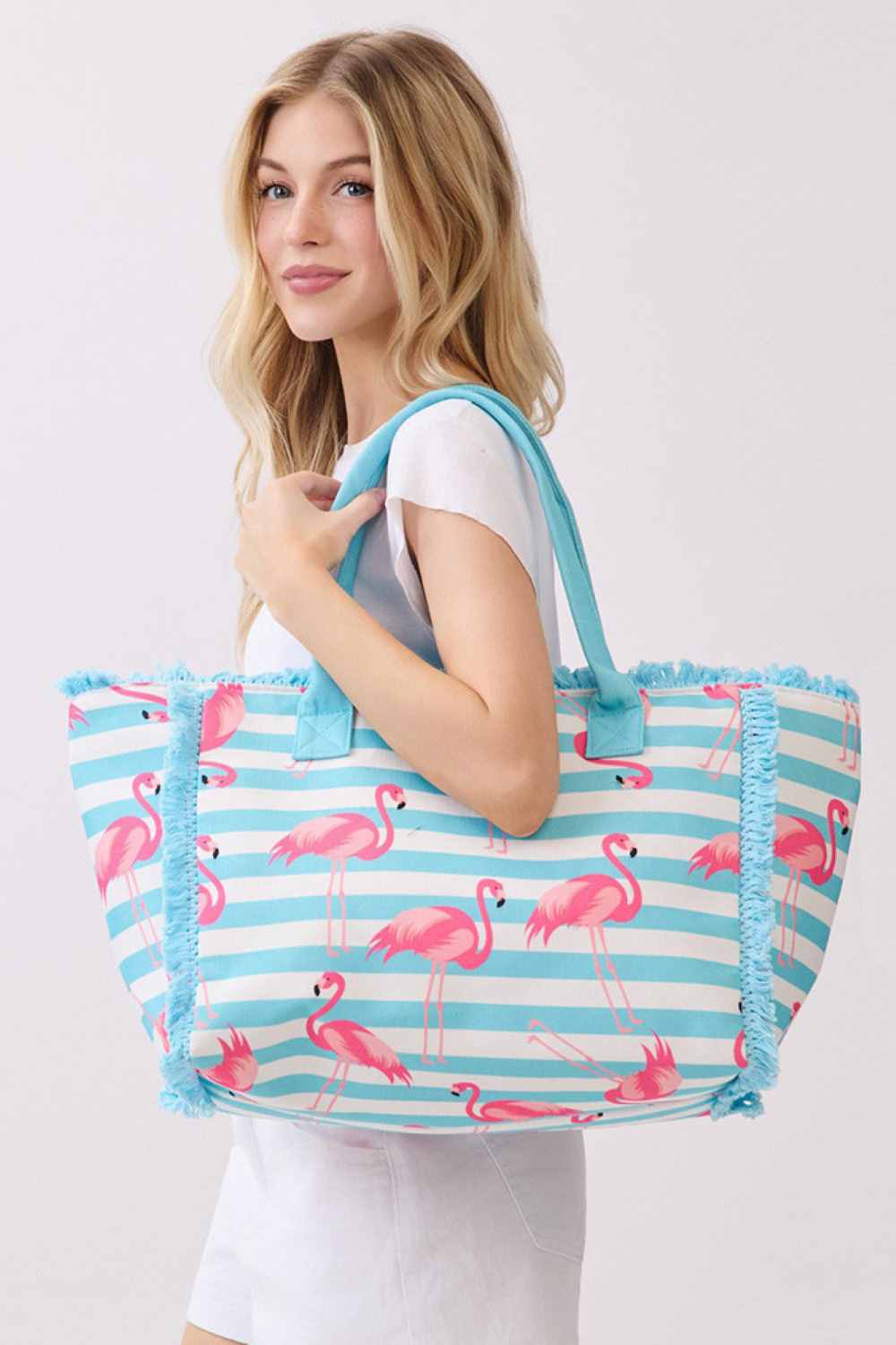 Blue Make a statement with this vibrant medium tote bag showcasing a tropical flamingo design with bold stripe patterns and eye-catching fringe trim. Built for durability with 100% polyester construction, this versatile bag measures 14.5" x 11.5" x 7" and features a reliable zipper closure plus an inner pocket for keeping valuables secure. Perfect for beach outings, weekend getaways, or daily adventures.