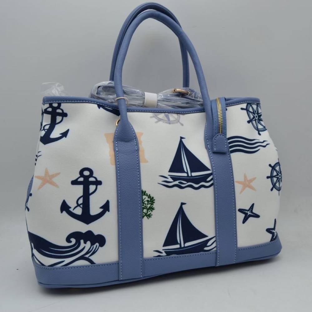 Blue Set sail with this nautical-inspired canvas tote. Featuring a crisp backdrop decorated with a classic print of anchors, sailboats, ship wheels, and ocean waves, this bag is the perfect accessory for coastal getaways or adding maritime flair to your daily ensemble. Framed with structured textured trim, it balances casual resort style with sharp, everyday functionality.