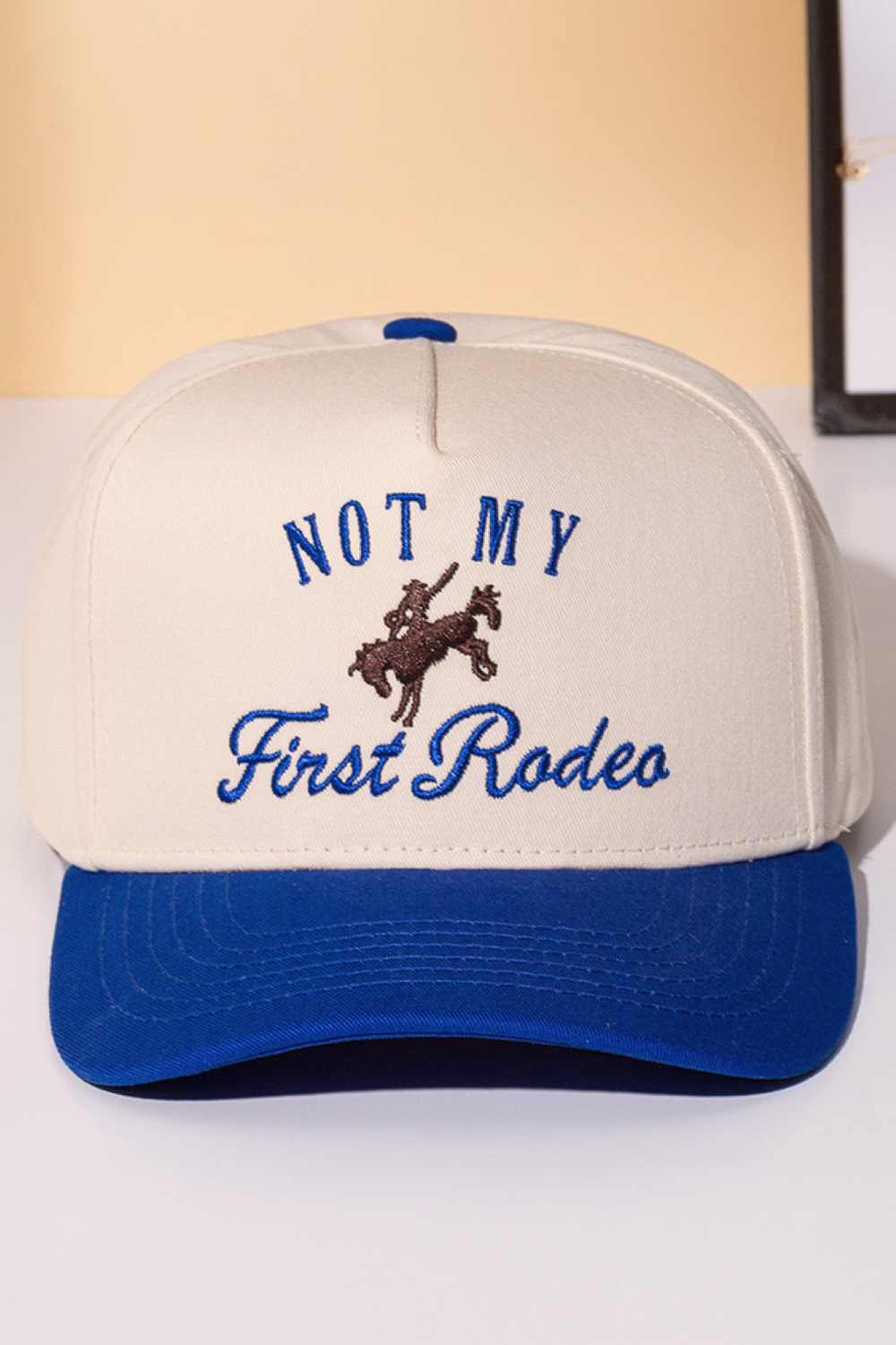 Blue Classic trucker cap with bold "NOT MY FIRST RODEO" embroidery across the front. Features a two-tone design that blends style with attitude. Crafted from 100% cotton for breathability and comfort. Snapback closure adjusts to fit most head sizes. Perfect for casual wear, outdoor adventures, or making a statement wherever you go.
