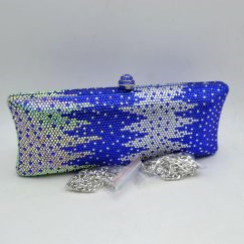 Blue-silver This structured clutch bag features an elongated silhouette with subtly flared edges, completely covered in fine, glittering micro-embellishments that create a shimmering, textured surface suitable for elegant everyday use. The central storage compartment is securely accessed via a hard-frame opening with an ornamental, rounded top clasp. A long, slender metallic curb chain strap is permanently attached to the top loops