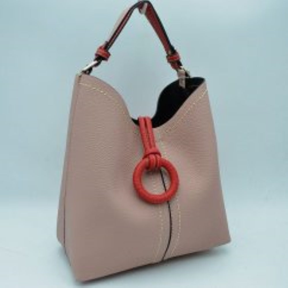 Blush This structured everyday bucket bag features a pebbled textured body with a distinctive curved, dip-top opening and prominent contrast stitching details along the front panel. It is designed with a singular flat top handle anchored to the sides by polished metal hardware loops for comfortable carrying. A central loop strap extends from the back to the front