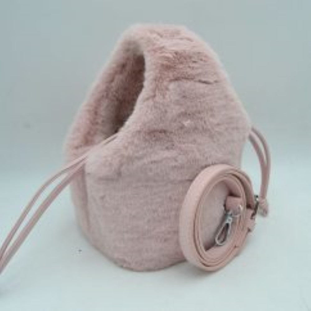 Blush This unique everyday bucket handbag features a soft, high-pile plush exterior that brings a cozy, tactile texture to your accessory collection. Designed with a rounded, structured silhouette, it features a central main storage compartment accessed through a flexible top opening with a drawstring cord tie for secure closure. For versatile carrying options, the bag includes an integrated top cutout handle alongside a separate, detachable shoulder strap equipped with metallic clasps.