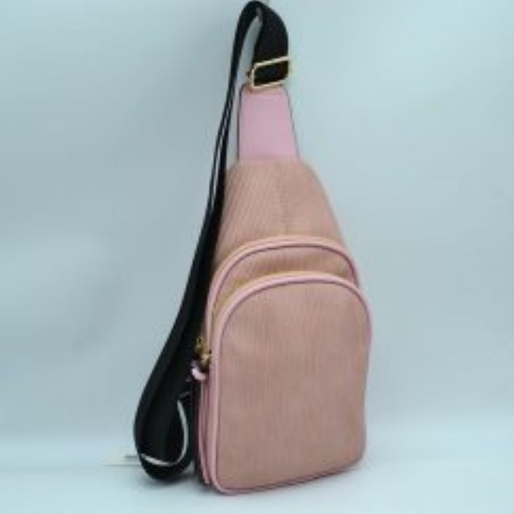 Blush This practical sling bag features a textured, finely ribbed exterior w/ a tapered silhouette designed for comfortable everyday use. It offers organized storage compartments, including a curved main zippered section and a matching smaller front zippered pouch, both enhanced by elongated vertical tassel pulls hanging from the sliders. The bag is equipped w/ a single wide fabric shoulder strap attached to a smooth top panel & secured w/ a metallic adjustment buckle to easily customize the carrying length