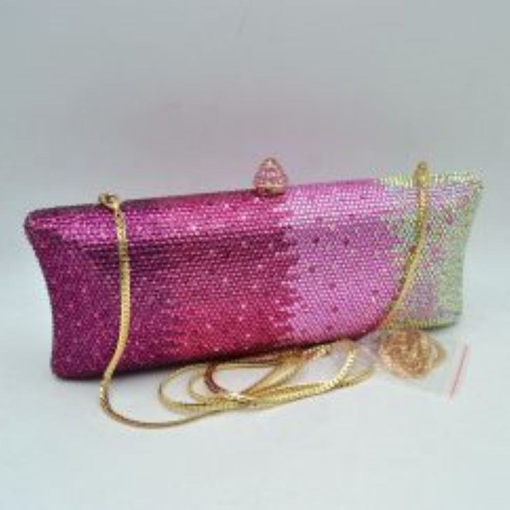 Blush-silver This structured clutch bag features an elongated silhouette with subtly flared edges, completely covered in fine, glittering micro-embellishments that create a shimmering, textured surface suitable for elegant everyday use. The central storage compartment is securely accessed via a hard-frame opening with an ornamental, rounded top clasp. A long, slender metallic curb chain strap is permanently attached to the top loops