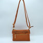 Brown This functional crossbody bag is designed for organized everyday use, featuring a textured exterior equipped with multiple secure storage compartments. The front panel includes a convenient horizontal zippered pocket accented with an oversized metallic zipper pull, situated beneath a decorative horizontal band detailed with metallic studs and loops.