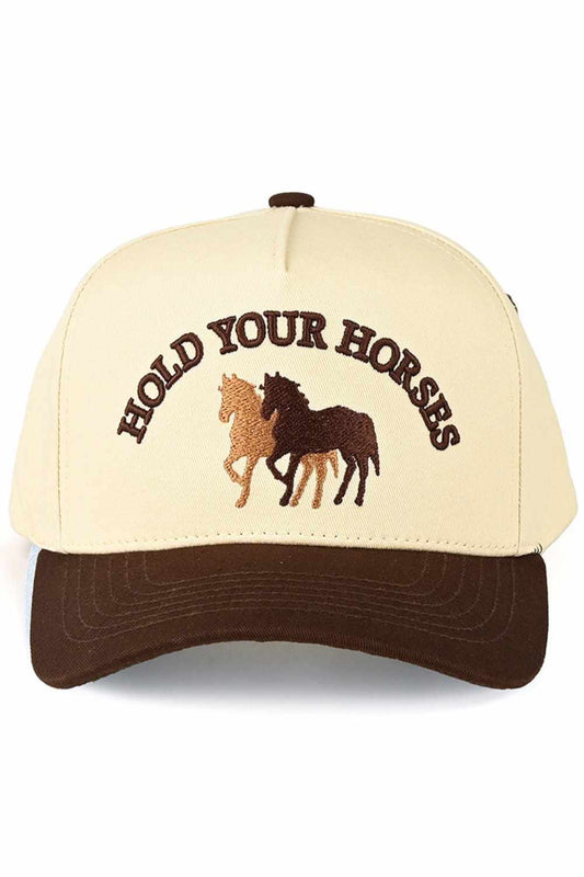Brown Classic two-tone trucker hat featuring bold "HOLD YOUR HORSES" embroidered lettering. Crafted from 100% cotton for breathable comfort all day long. Snap back closure adjusts to fit most head sizes with a circumference of 22.5". Structured design with mesh panels keeps you cool. Perfect for casual wear, outdoor adventures, or adding personality to any outfit.&nbsp;
